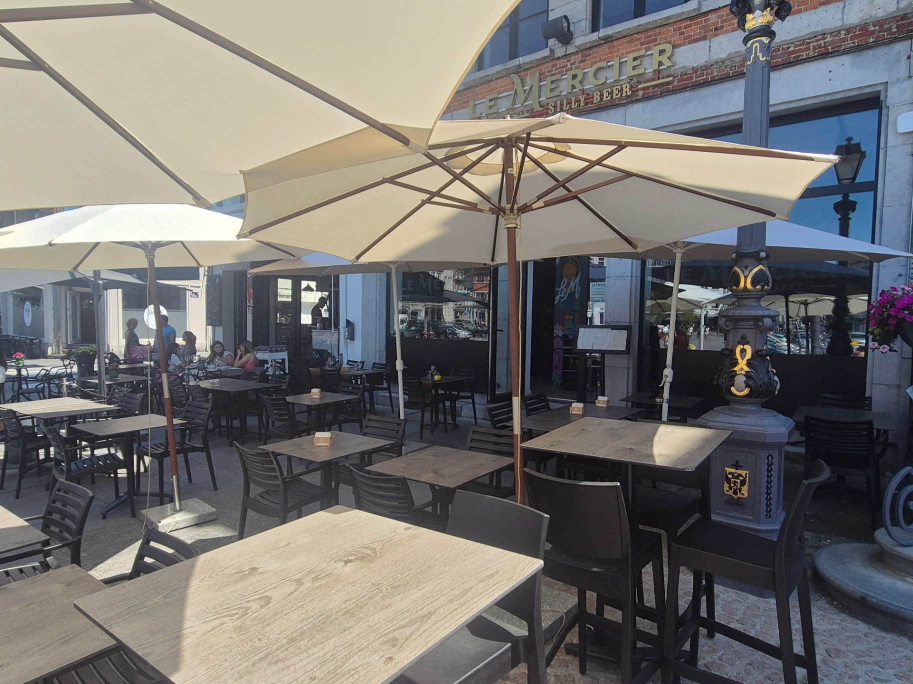 Parasols crème alignés et lampadaire orné devant Le Mercier