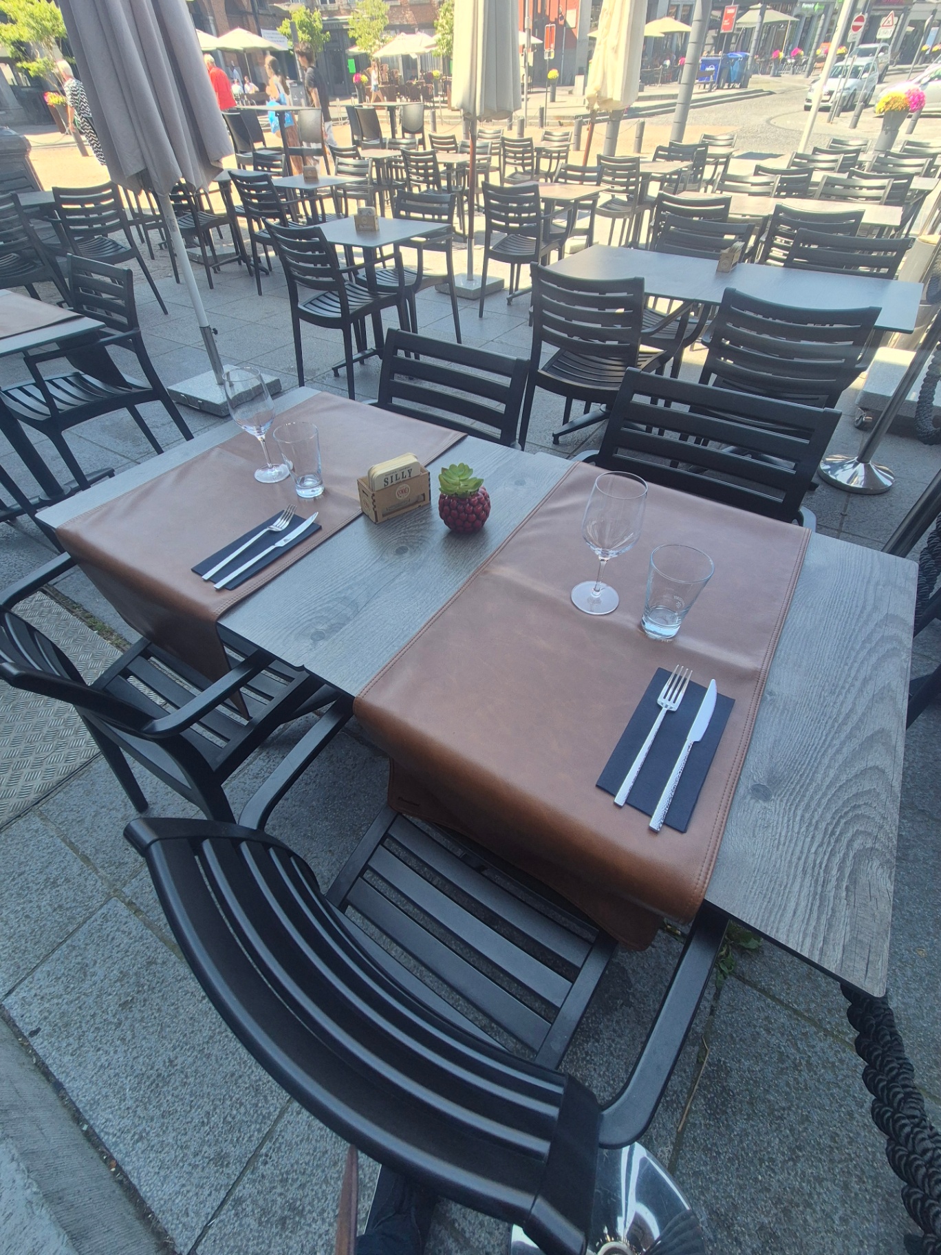 Table dressée en terrasse avec sets en cuir et verres, ambiance chaleureuse
