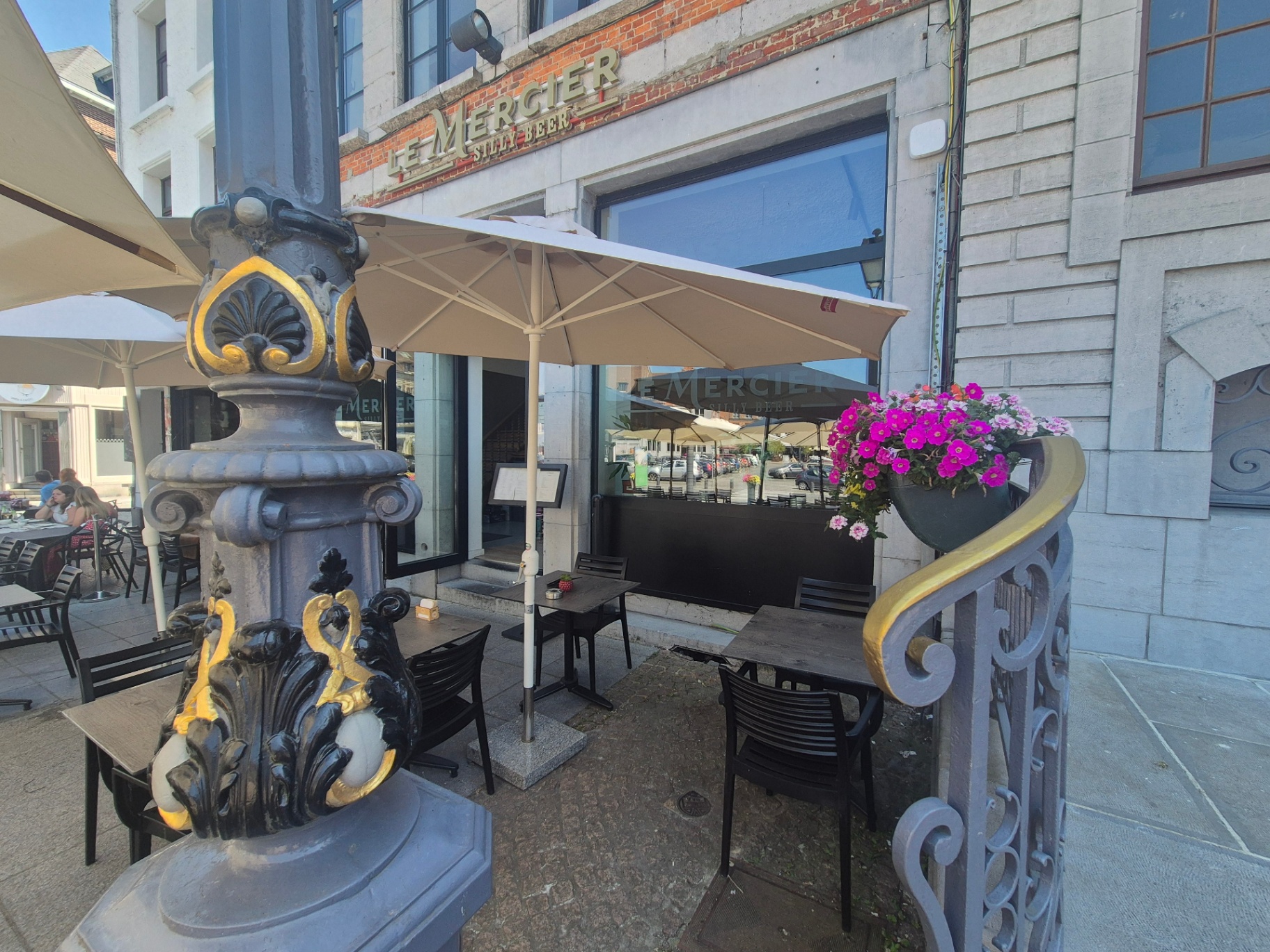 Détail des lampadaires ornés et parasols crème devant l'enseigne Le Mercier