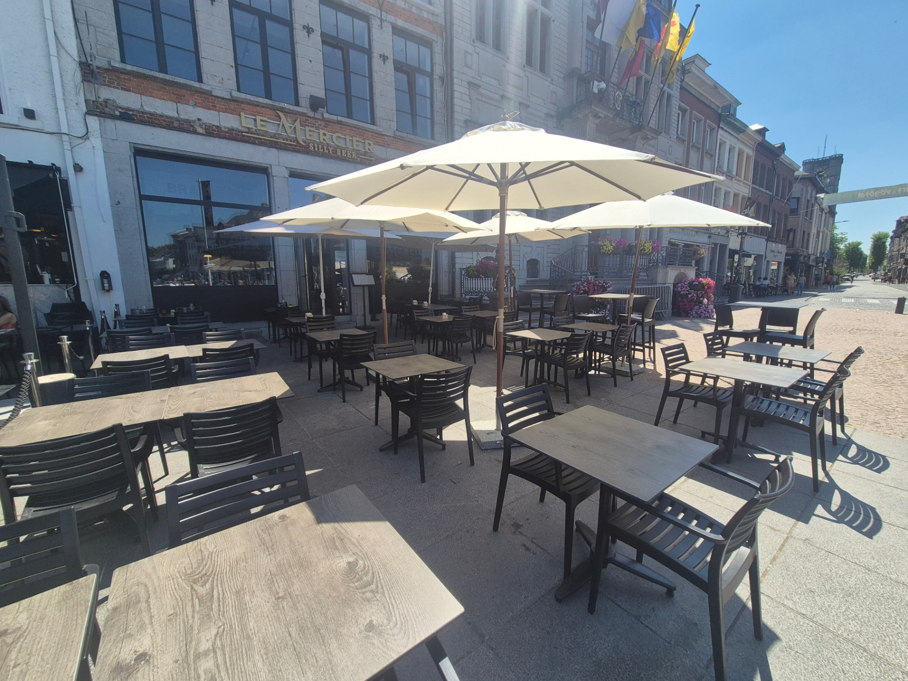 Terrasse ensoleillée face à l'Hôtel de Ville d'Ath et ses drapeaux