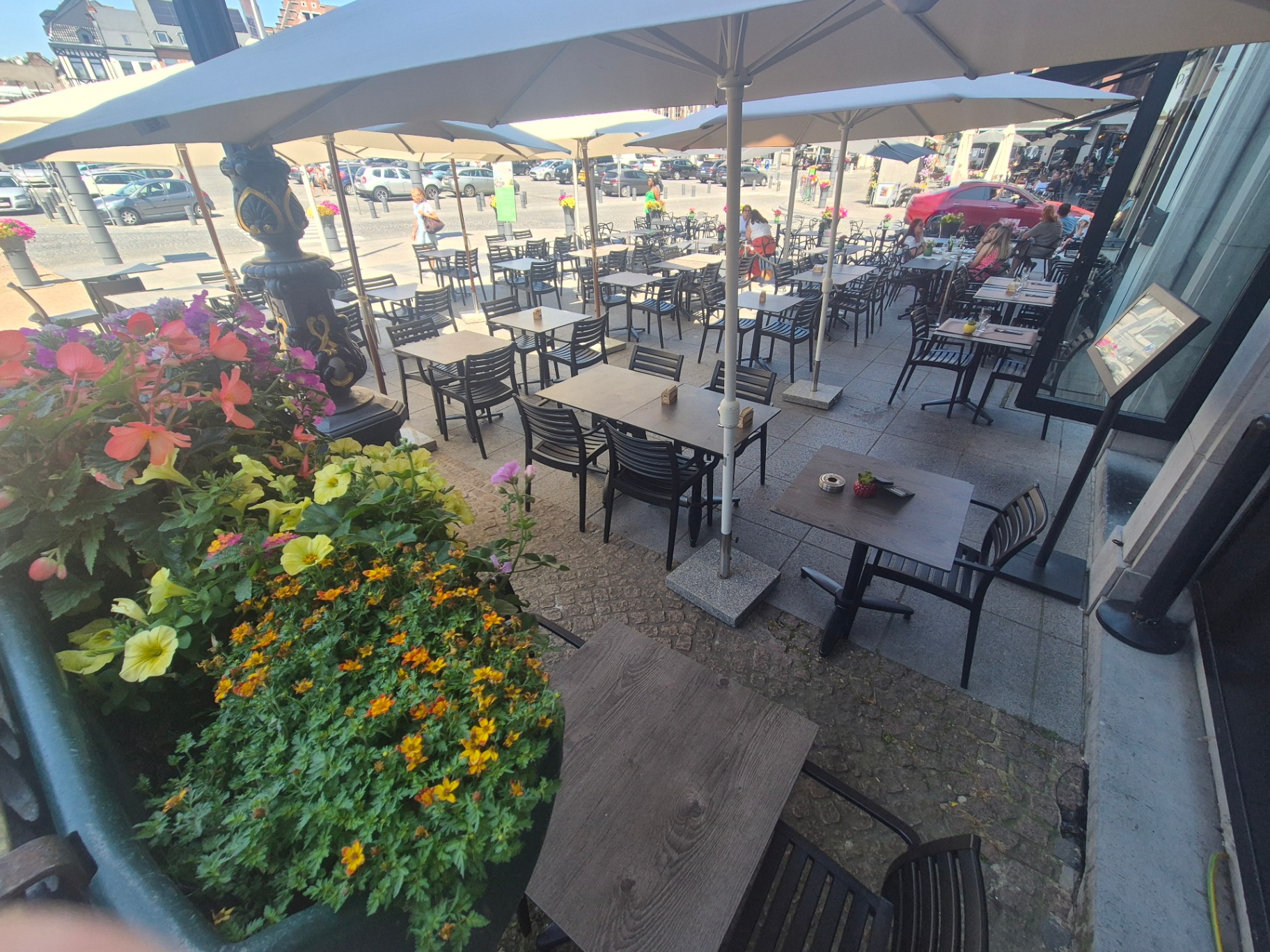 Terrasse fleurie avec vue plongeante sur les tables et la Grand-Place